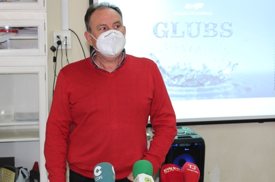 Un hombre con jersey rojo y mascarilla ante micrófonos de diferentes medios de comunicación